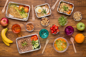 Healthy food in foil boxes on wooden background