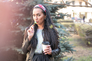 Happy and cute adult girl walking with lollipop and coffee in firtree