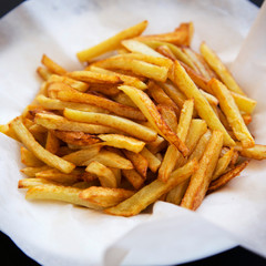 Homemade french fries on a baking sheet on a black background, side view. Close-up.