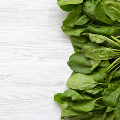 Washed fresh spinach leaves on a white wooden table, top view. From above, overhead. Copy space.