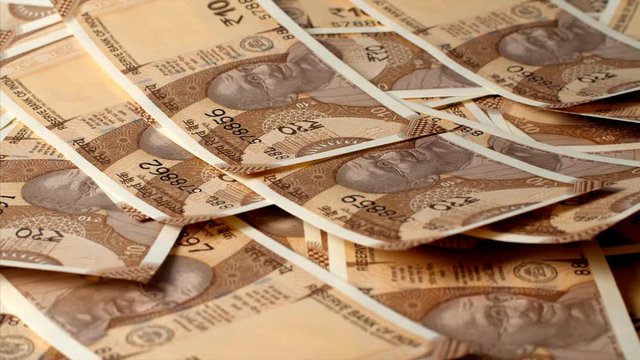 Indian Currency of Rupee 10 notes falling on a table. 