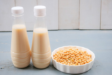 Bottle of soy milk and soybean on wooden table