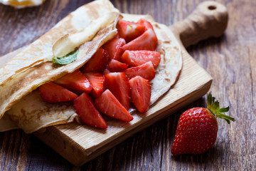 Breakfast or brunch, crepes with fresh summer strawberries and powdered sugar