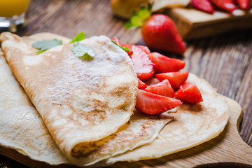 Breakfast or brunch, crepes with fresh summer strawberries and powdered sugar