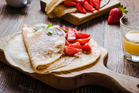 Breakfast or brunch, crepes with fresh summer strawberries and powdered sugar