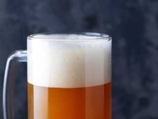 Beer mug unfiltered wheat beer close-up with a large foam cap