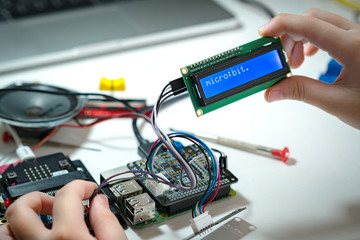 Close up hands of preteen / teenage successfully code and connect blue character LCD display screen...
