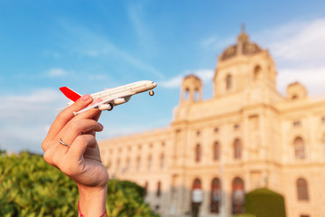 Happy young Asian girl with a toy airplane posing against the backdrop of a historic building in a European city. Travel and Air tourism transport Concept