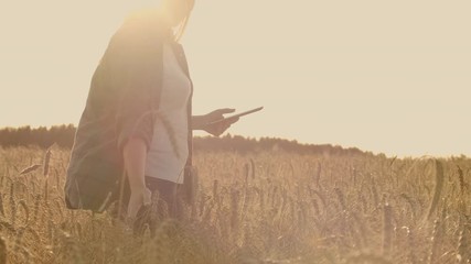 Close-up of a woman at sunset touches the wheat germ and makes the data in the tablet