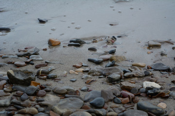 Pebble stones on sandy river bank.