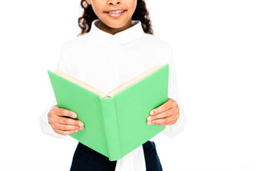 Fototapeta premium cropped view of smiling african american schoolgirl holding book isolated on white
