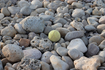 Fototapeta na wymiar Tennis ball over round rocks