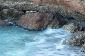 Naklejka premium Waves hitting the rocks in a small beach. Long exposure shot.