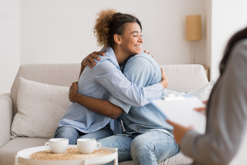 Young Black Spouses Hugging On Sofa After Successful Couples Therapy