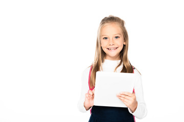 Fototapeta premium adorable schoolgirl halding laptop and smiling at camera isolated on white