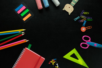 Back to school. The various stationery on blackboard background.