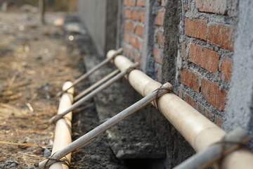 Strong bamboo ladder lay in under construction house beside brick wall