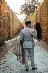 Happy young couple in love. Guy hugging a girl. The guy holding his girlfriend in his arms. Romantic relationship. Man in a grey suit. Pretty woman in a beautiful elegant dress.  Love story. 