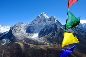 Bunte Landschaft mit dem hohen Himalaya-Berg Ama Dablam, wunderschönes Tal mit blauem See und bunten Gebetsfahnen im Vordergrund