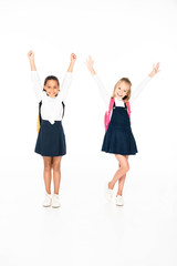 Fototapeta premium full length view of two happy multicultural schoolgirls showing yes gestures on white background