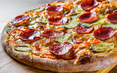 Pepperoni Pizza with Mozzarella cheese, salami, bacon, Tomato sauce, pepper, Spices and pickled cucumbers. Italian pizza on wooden table background