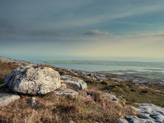 Burren National park, View from a mountain on Galway bay, Calm cloudy sky, Rough terrain and big stones in foreground. Concept travel, hiking,