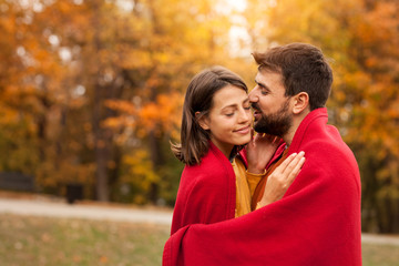 Happy couple in love standing outside and man wrapping his woman