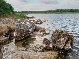 Big stone on river Corrib shore, county Galway, Ireland. Cloudy sky,