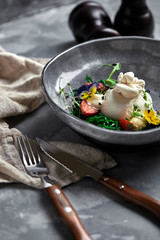 Burrata salad with strawberries and seaweed, on a gray background. Salad with buratta cheese on a gray plate and concrete marble background.