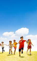 Fototapeta premium Multiethnic group of school children running on the grass