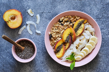 Granola with milk and fruit, chia seeds and coconut on a concrete background.