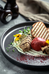 Duck paste with ice cream and grilled white bread croutons. Close-up, low key, gray background.