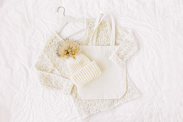 Knitted white sweater with hat and tote bag. Autumn/winter fashion clothes collage on white background. Top view flat lay.