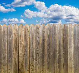 Rustic wooden fence with blue sky and clouds