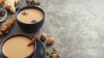 Cup of traditional indian masala chai tea with ingredients: cinnamon, cardamom, anise, nutmeg. With copy space