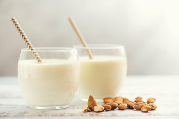 Almond milk in glasses with almond on a light wooden table