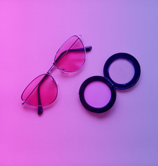 Rouge and sunglasses are toned on trendy neon colors – pink, violet and blue. Makeup and fashion concept. Flat lay 