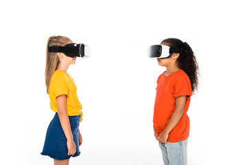 two multicultural friends looking at each other while using virtual reality headsets isolated on white