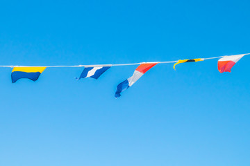 Nautical flags on the ship against blue sky