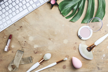 Women's blog concept. Office table with flowers, make up brush and cosmetics.