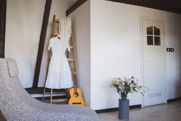 Modern bridal fashion. White wedding dress hanging in the hotel room.