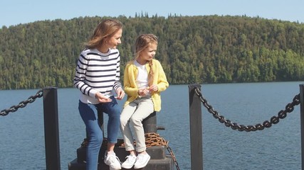 Happy mother spends time with her baby lying on the pier during summer vacation.