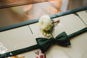 Wedding fashion for men. Top view of boutonniere and bow tie on wooden background.
