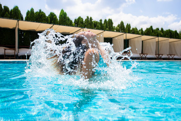 Beautiful young woman diving out of a swimming pool