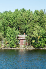 Fototapeta na wymiar Red small finnish wooden house on island on the lake Saimaa. Lappeenranta, Finland.