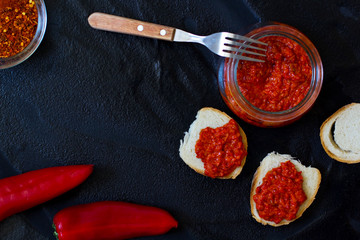 ajvar, appetizer of baked peppers on a black background, bread with ajvar, toast with ajvar, balkan appetizer of baked peppers, top view, space for your text