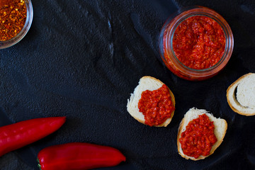 ajvar, appetizer of baked peppers on a black background, bread with ajvar, toast with ajvar, balkan appetizer of baked peppers, top view, space for your text