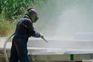 Fototapeta na wymiar Worker is remove paint by air pressure sand blasting
