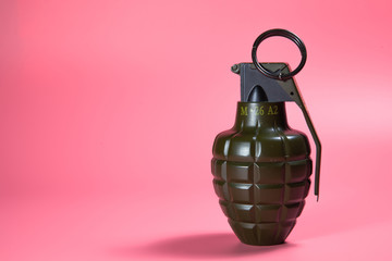 Green metal hand Grenade with round pin over When I pull out it will blow Bomb On a pink background
