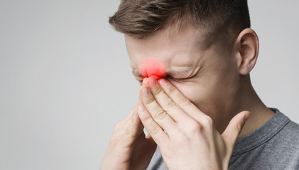 Stressed young man suffering from sore nose